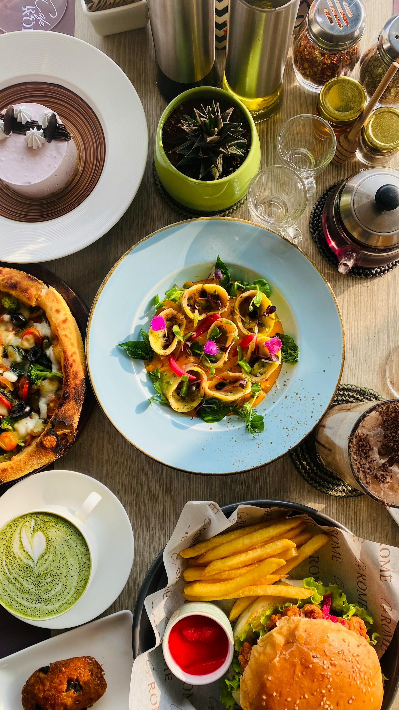 Restaurant table spread with multiple plated dishes, drinks, and a lively hospitality mood.