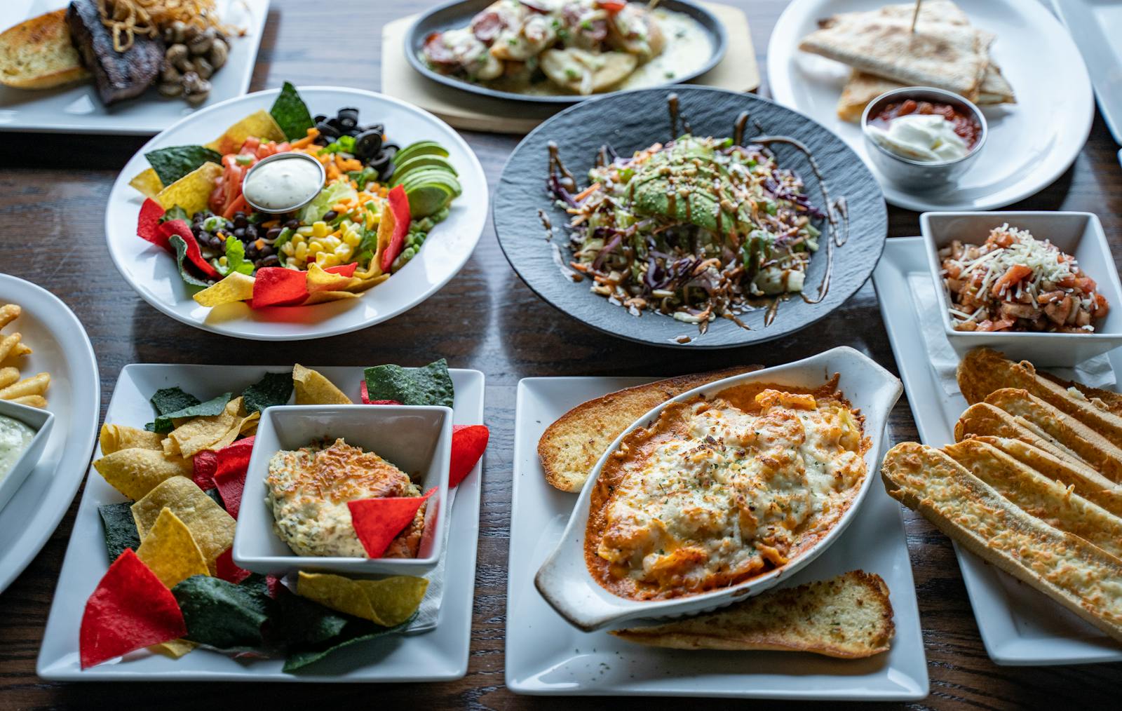 Colorful restaurant table full of shared dishes, sides, and appetizers for menu highlights.
